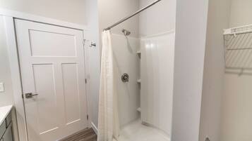 Un baño con ducha, una puerta y un perchero para toallas.