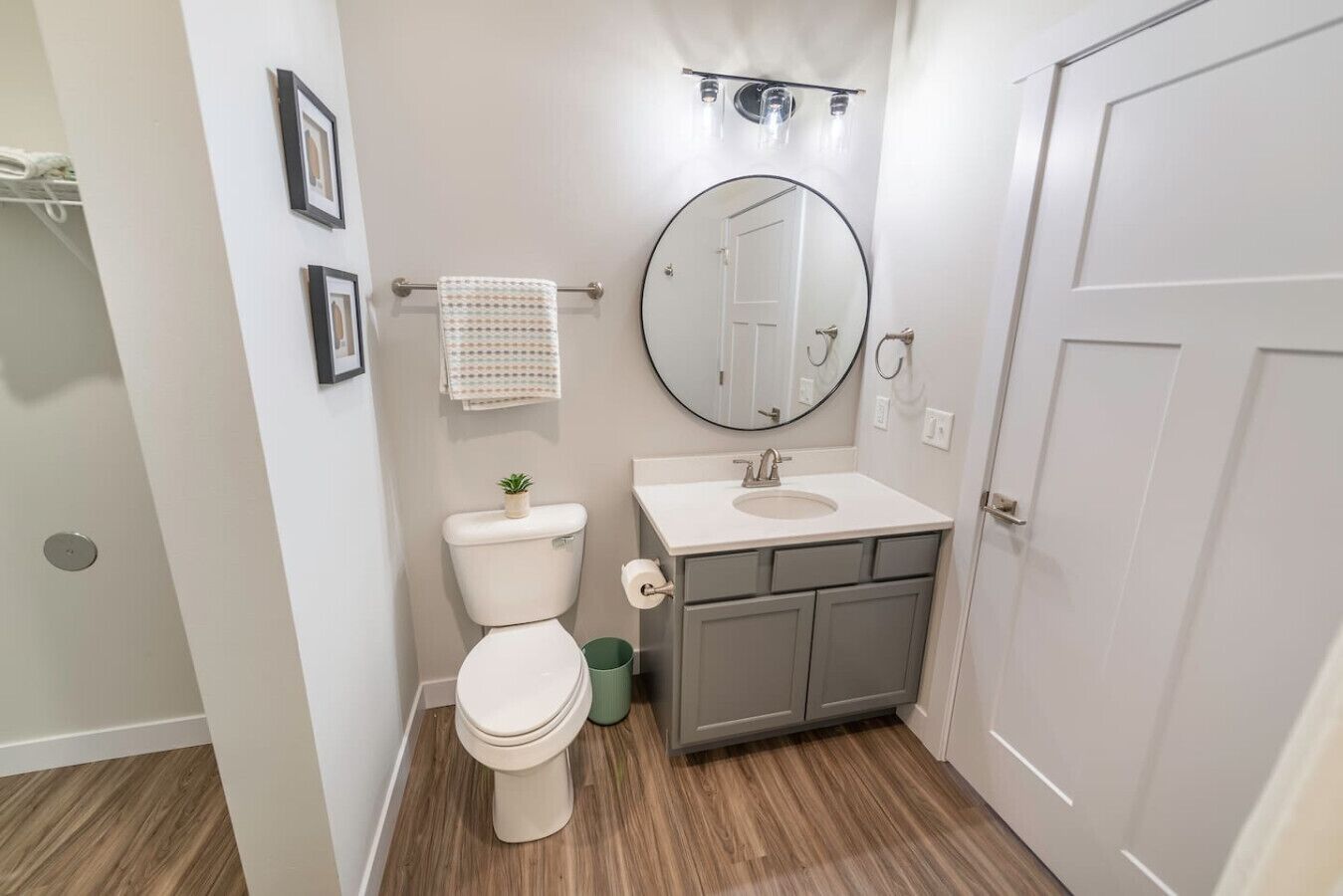 A bathroom with a toilet, sink, mirror, and a towel rack.