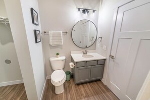 Un baño con inodoro, lavabo, espejo y toallero.