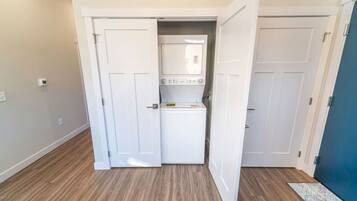 Een wasserette met een wasmachine, twee deuren en een houten vloer.