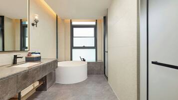A modern bathroom with a large bathtub, a vanity with a mirror, and a window providing natural light.