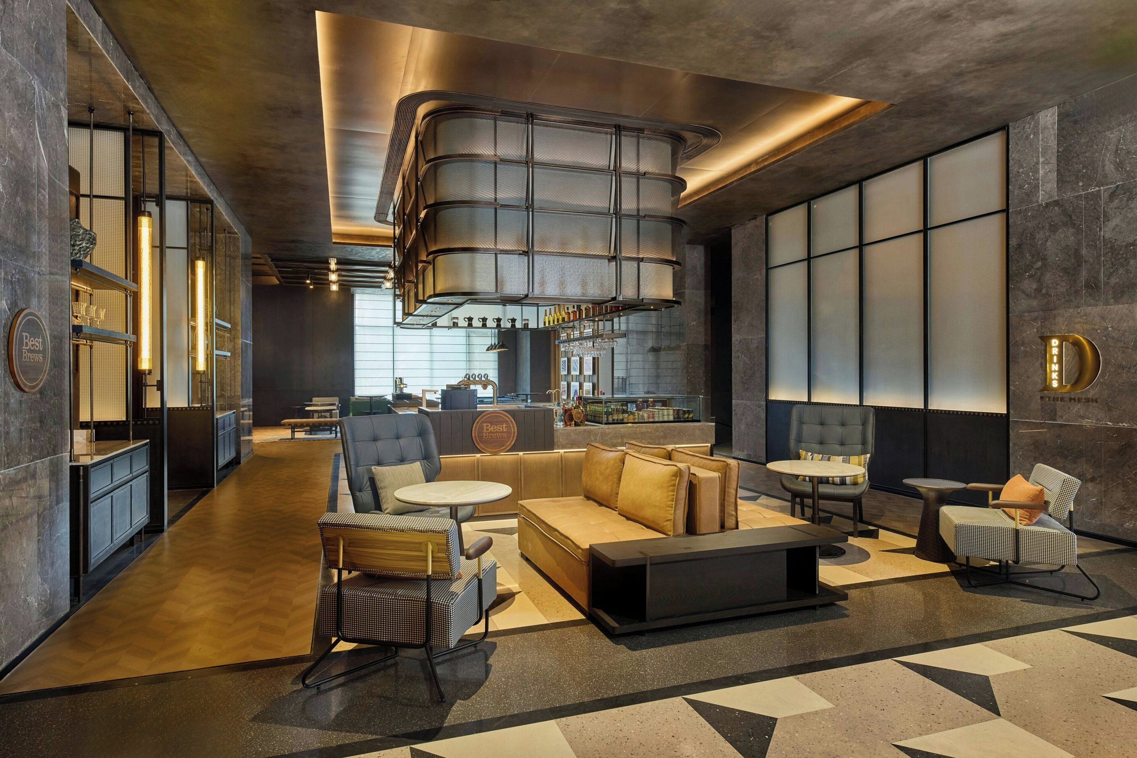 A modern hotel lobby with a seating area, a bar, and a reception desk.
