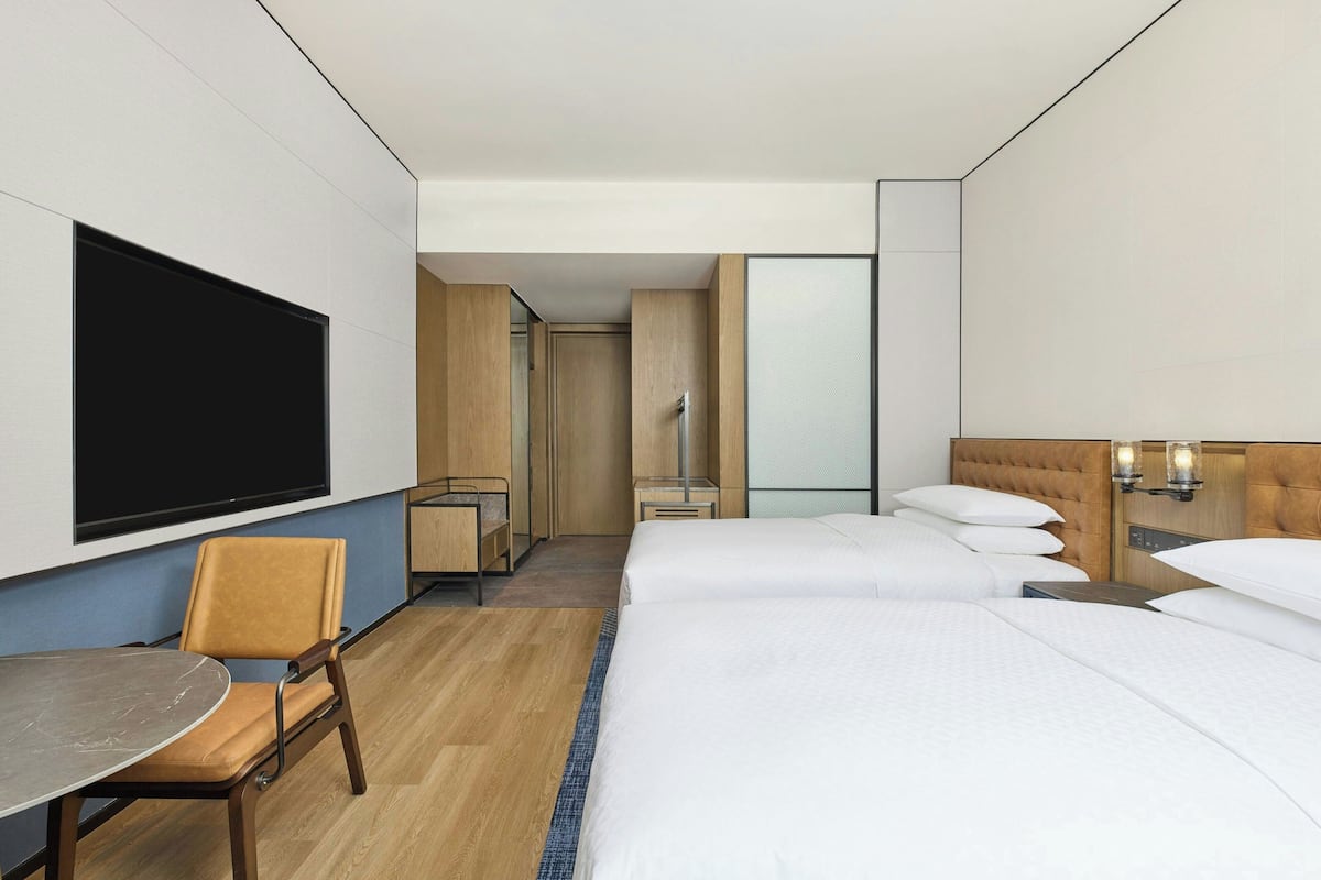 A hotel room with a bed, a desk, a chair, and a TV.