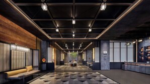Eine moderne Lobby mit einem geometrisch gemusterten Boden, einer zentralen Sitzecke und einem Empfangsbereich.