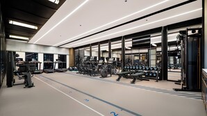 Ein Fitnessstudio mit Laufbändern, Kraftgeräten und Kurzhanteln.
