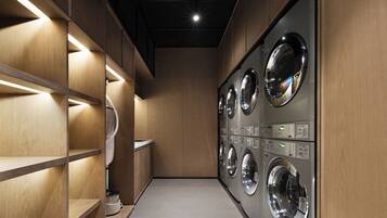 A laundry facility with multiple washing machines, wooden shelving, and built-in lighting.