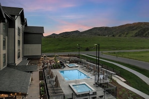 A pool area with multiple pools, outdoor seating, and a view of the surrounding landscape. - Springhill Suites By Marriott Steamboat Springs (Steamboat Springs)