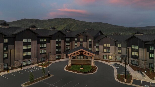 A multi-story hotel with a central courtyard, parking lot, and mountainous backdrop. - Springhill Suites By Marriott Steamboat Springs (Steamboat Springs)