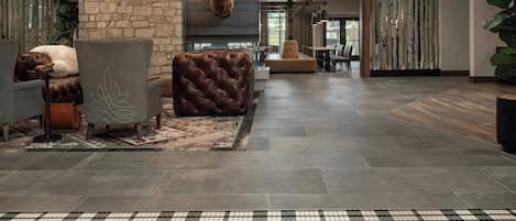 A lobby with a stone wall, a mounted deer head, leather seating, and a checkered floor with 'You have arrived' text.
