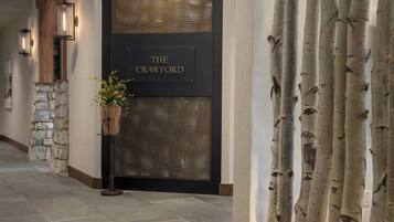 Un pasillo con una pared de piedra, una puerta con la leyenda 'THE CRAWFORD' y una planta en maceta.