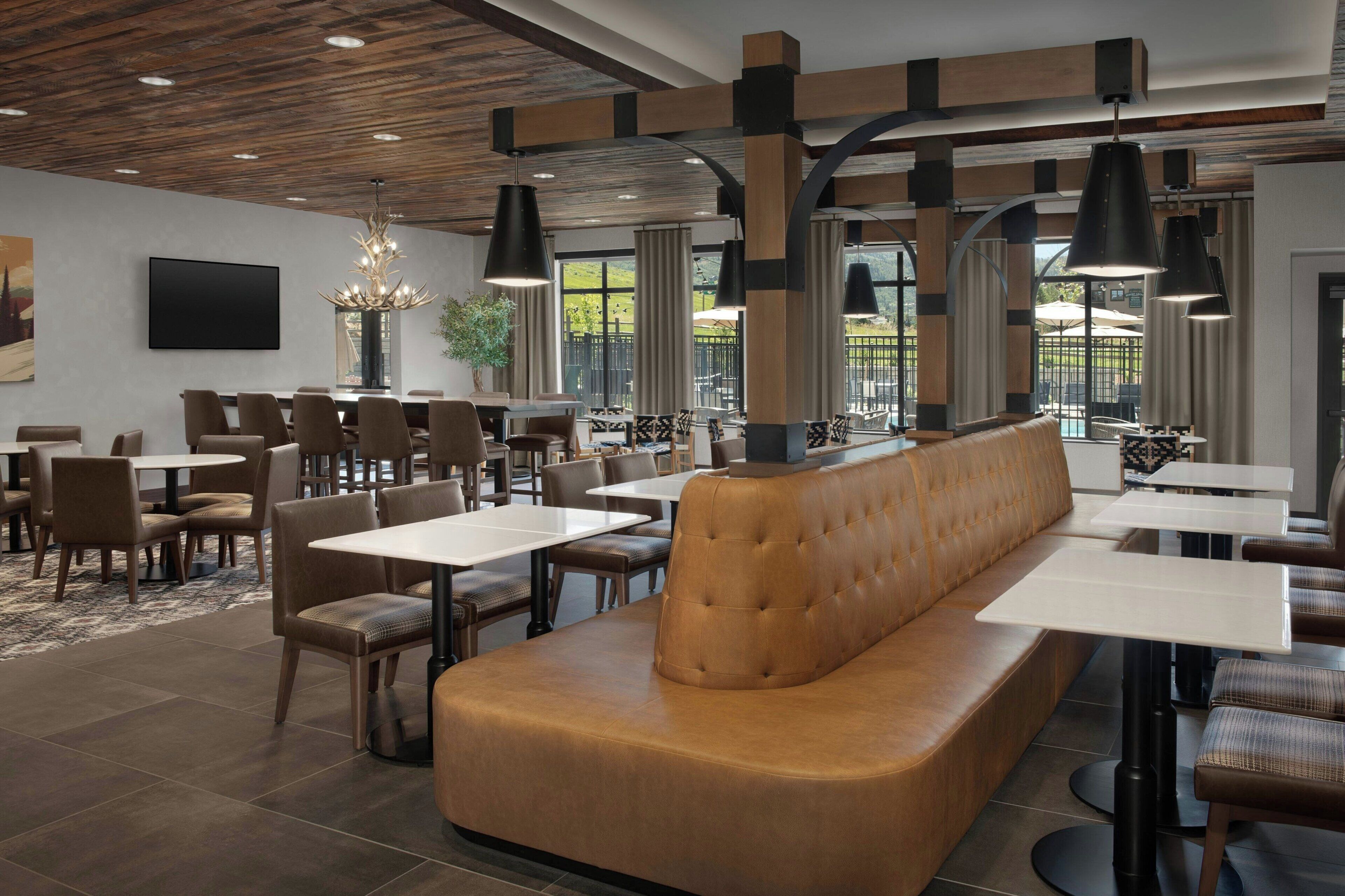 Interior moderno de restaurante con una zona central de mesas, varias mesas y lámparas colgantes.