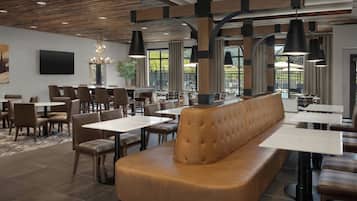Interior moderno de restaurante con una zona central de mesas, varias mesas y lámparas colgantes.
