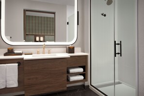 A modern bathroom with a large mirror, a sink, a shower, and a vanity with storage. - Springhill Suites By Marriott Steamboat Springs (Steamboat Springs)