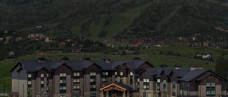 Un hotel de varios pisos con un vestíbulo central, rodeado por un paisaje montañoso.