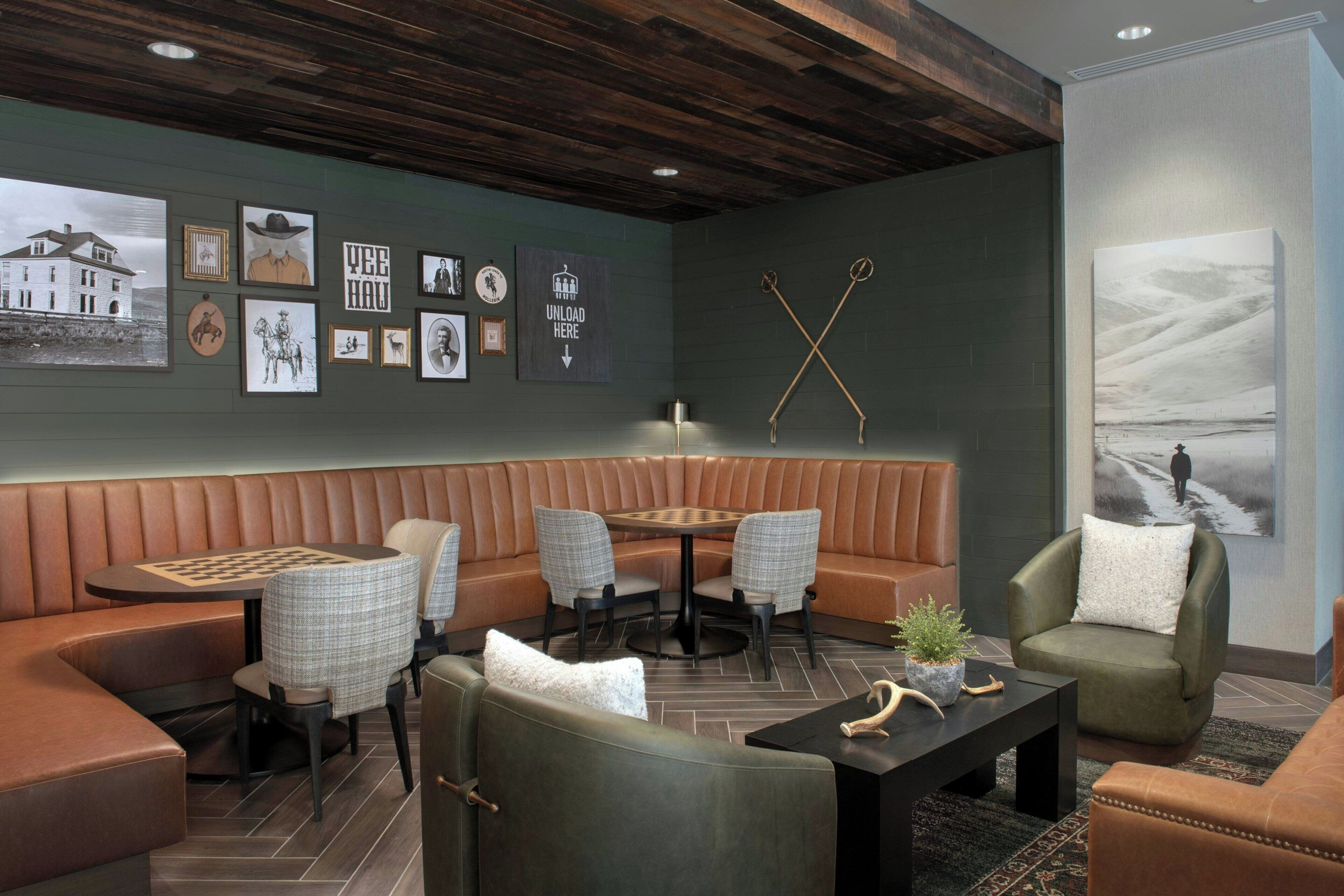 Un espace lounge moderne avec des banquettes en cuir, une table ronde et un assortiment de tableaux encadrés accrochés aux murs.