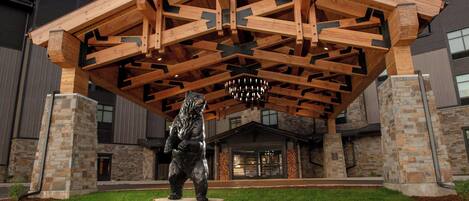 A building with a wooden roof structure, stone pillars, and a bear statue in front.