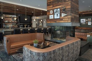 A bar area with a wooden ceiling, a fireplace, and a seating area with leather couches and a coffee table. - Springhill Suites By Marriott Steamboat Springs (Steamboat Springs)