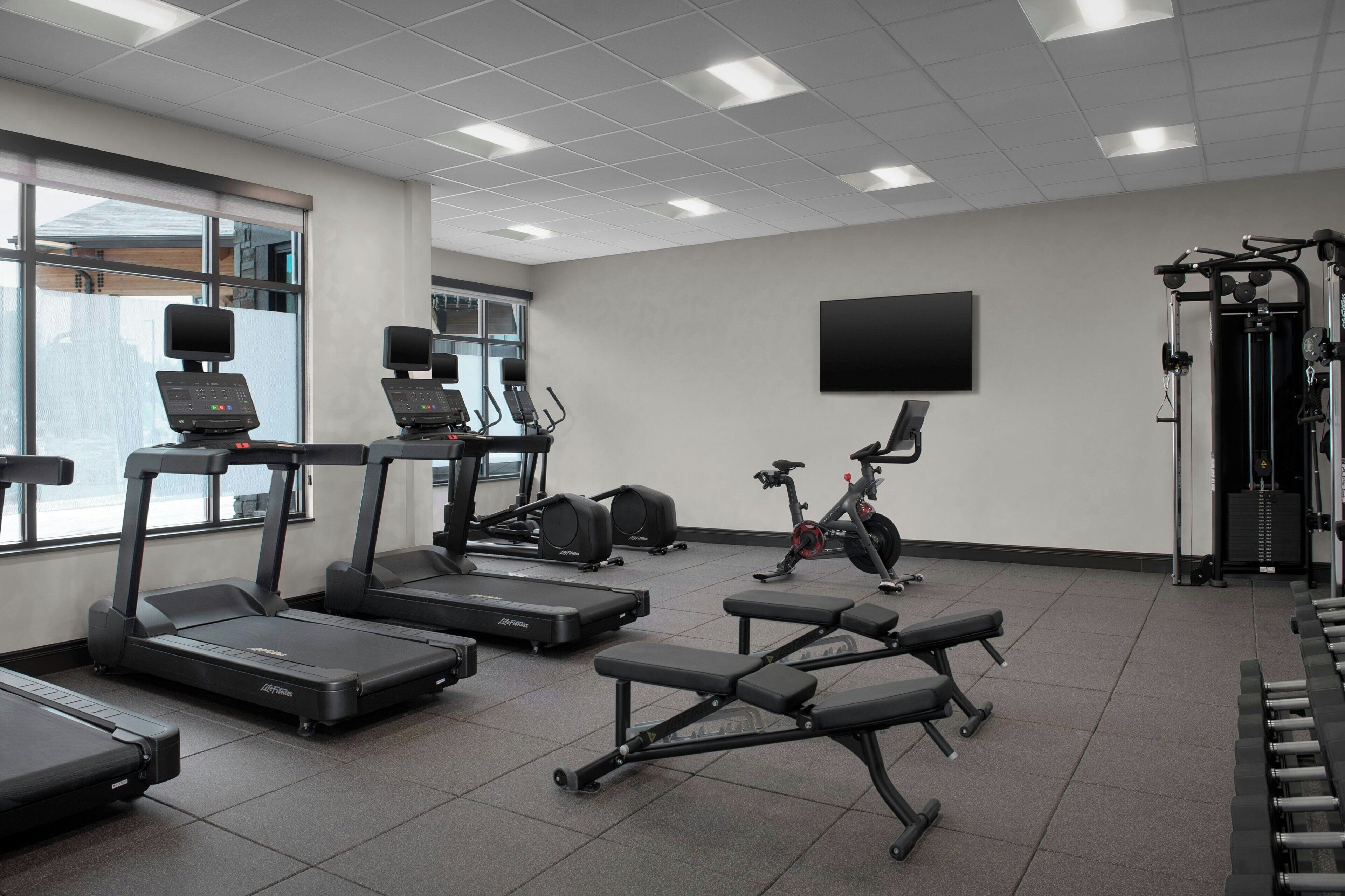 A gym with treadmills, a stationary bike, and weight benches.