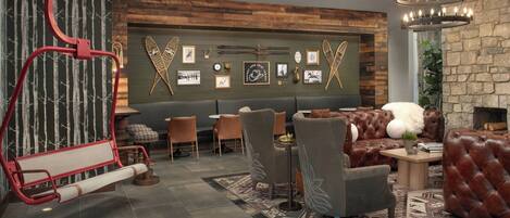Un espacio lounge moderno con sofás de cuero, un muro decorativo de madera y diversas decoraciones en la pared.