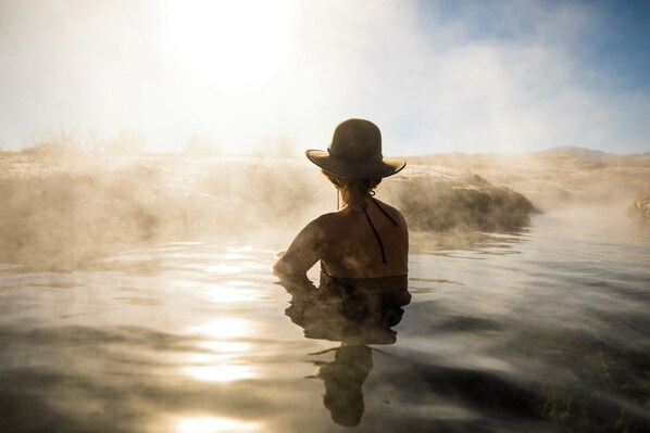 Una persona de pie en el agua, rodeada de vapor.