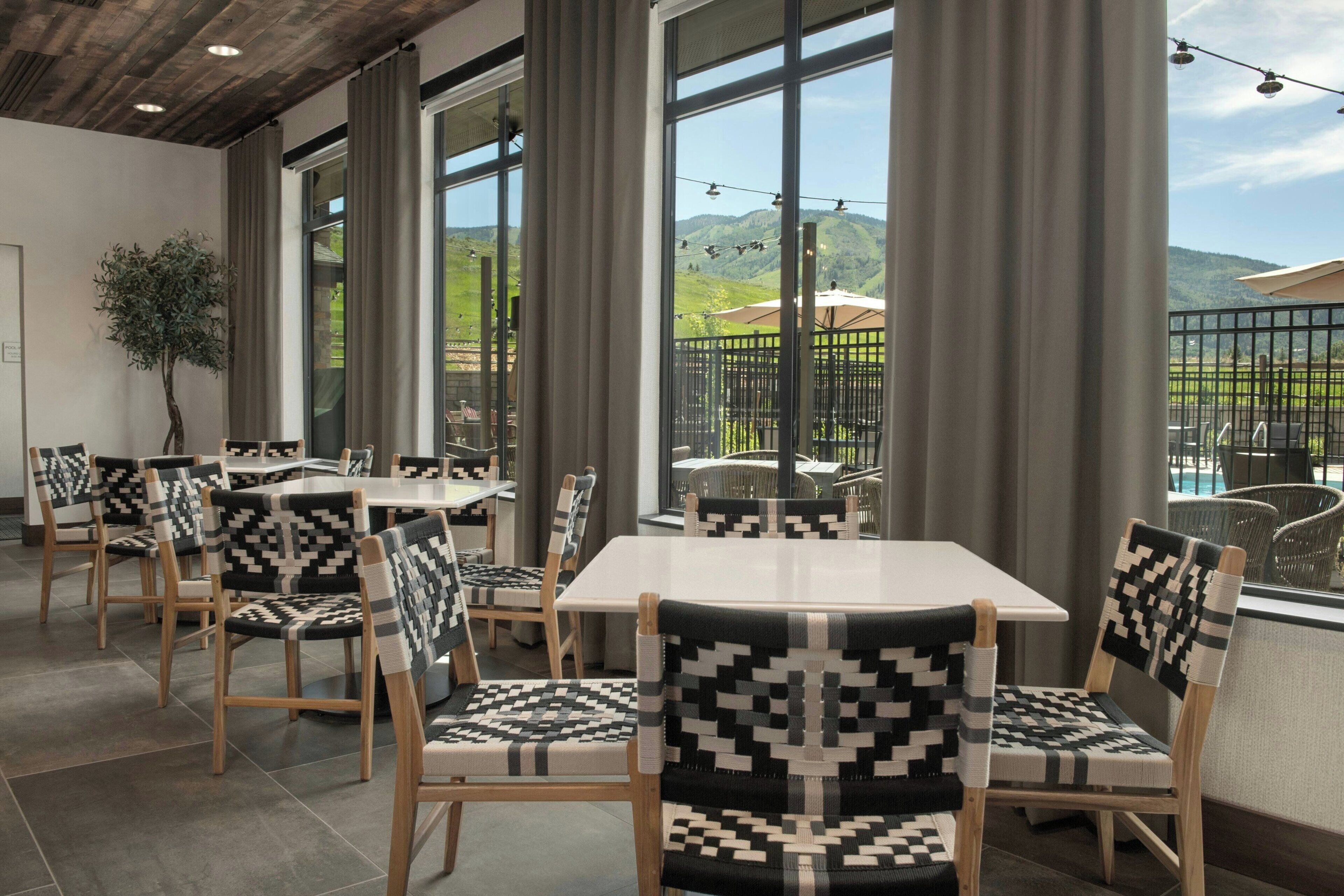 Un restaurante con amplios ventanales, sillas de madera y vistas al exterior.
