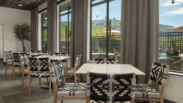 Un restaurante con amplios ventanales, sillas de madera y vistas al exterior.