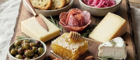 Tábua de madeira com diversos queijos, carnes, azeitonas e pão.