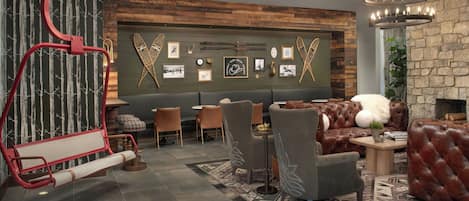 A modern lounge area with a red swing, leather sofas, a dining table, and a wall decorated with framed pictures.