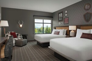 Habitación de hotel con dos camas, un escritorio, una silla y ventana con vistas.