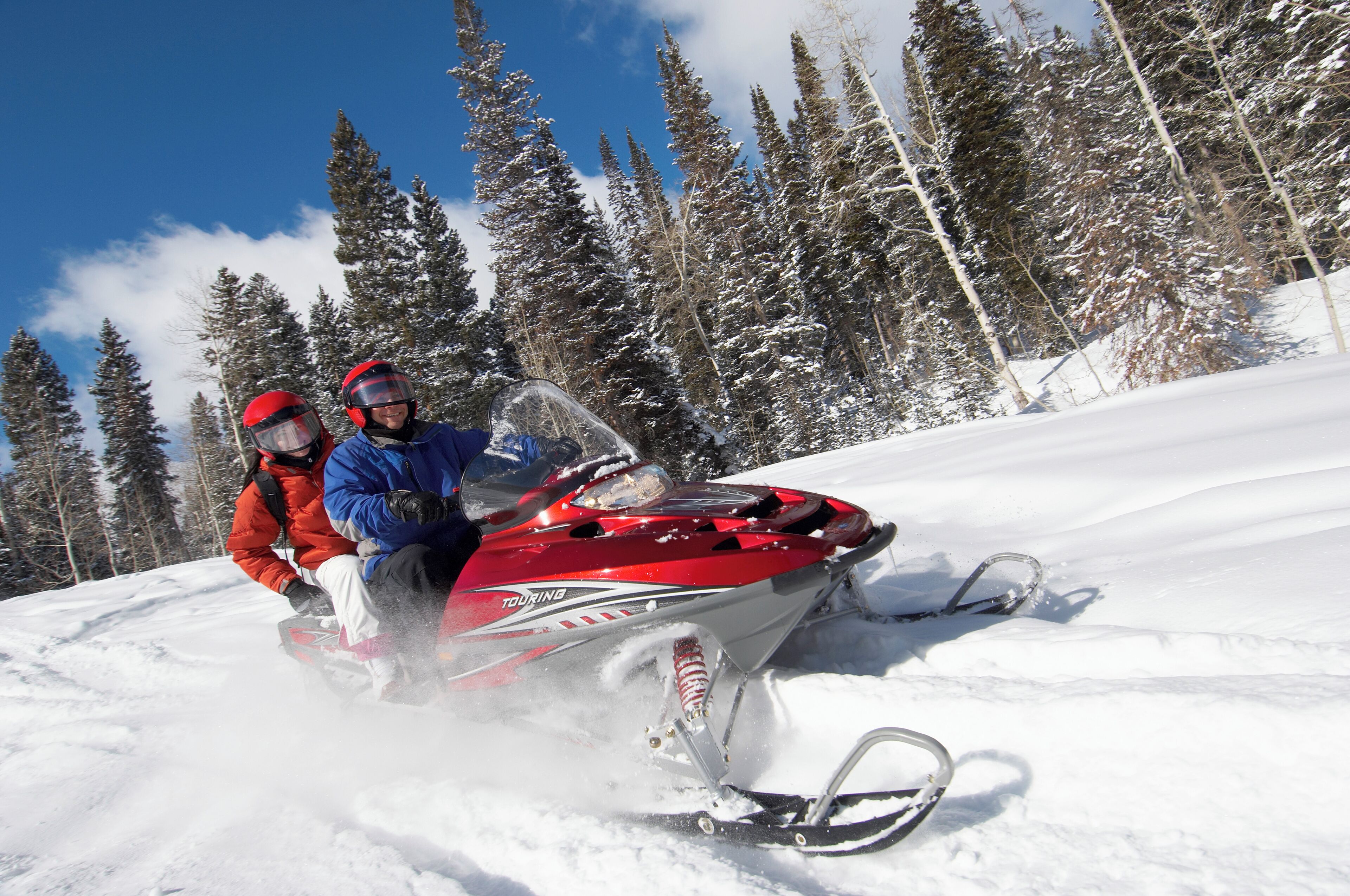 Dos personas practican motos nieve en una ladera nevada.