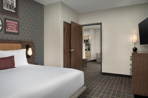 A hotel room with a bed, a wooden wardrobe, a television, and a wall-mounted lamp. - Towneplace Suites By Marriott Steamboat Springs (Steamboat Springs)
