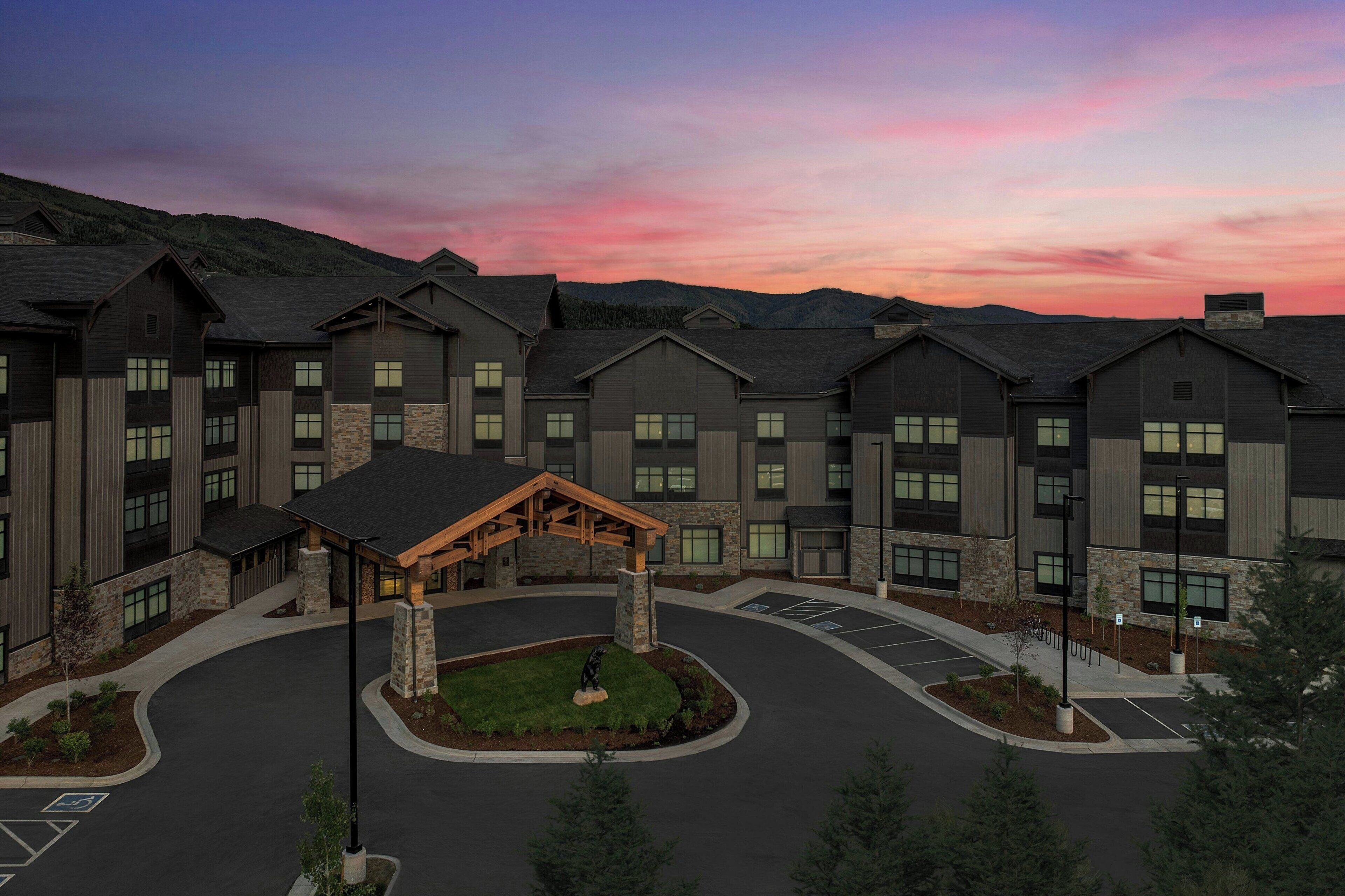 A multi-story hotel with a central courtyard and a parking area.