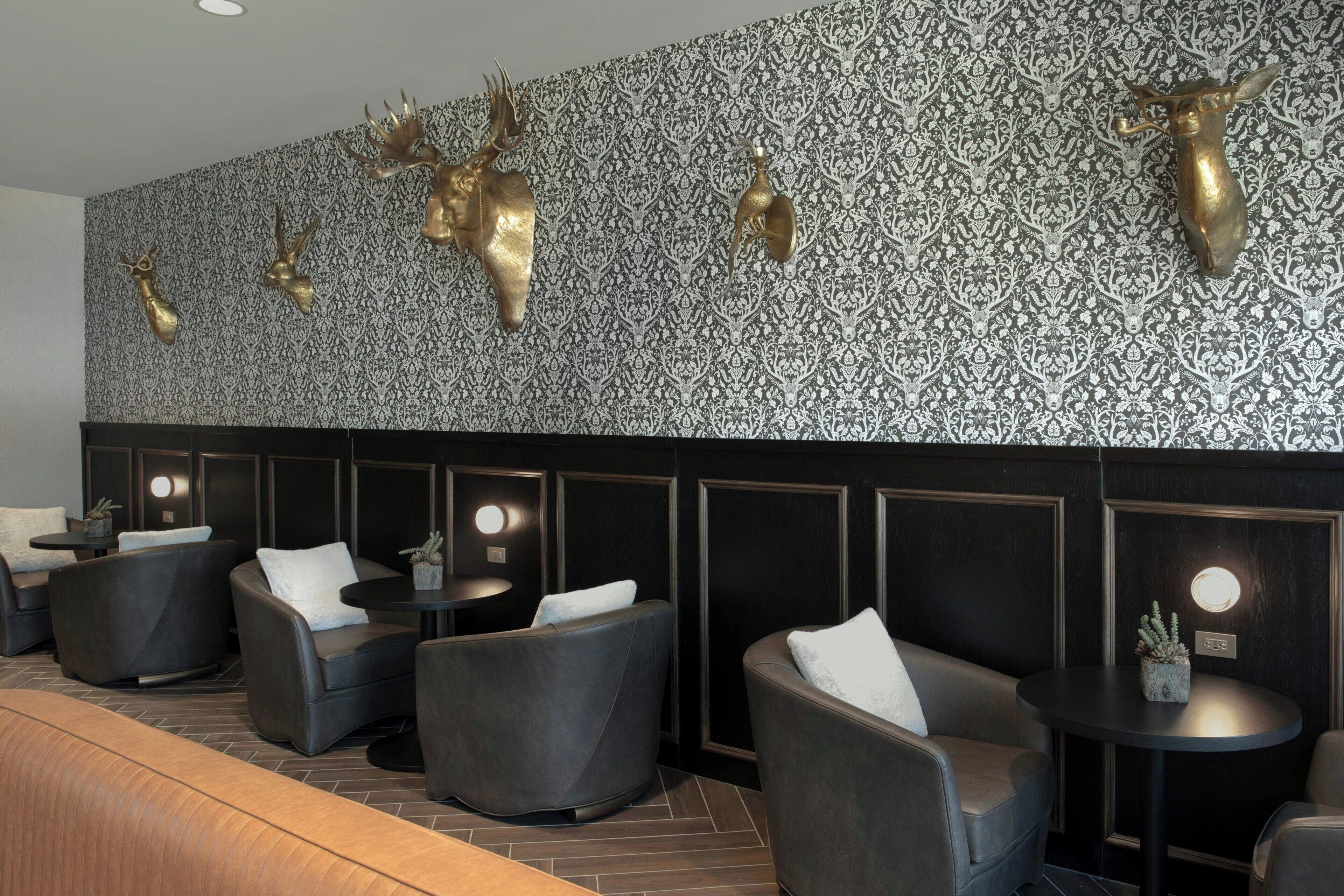 Un espace détente moderne avec des sièges en cuir, un mur à motifs et des éléments décoratifs en forme de bois de cerf.