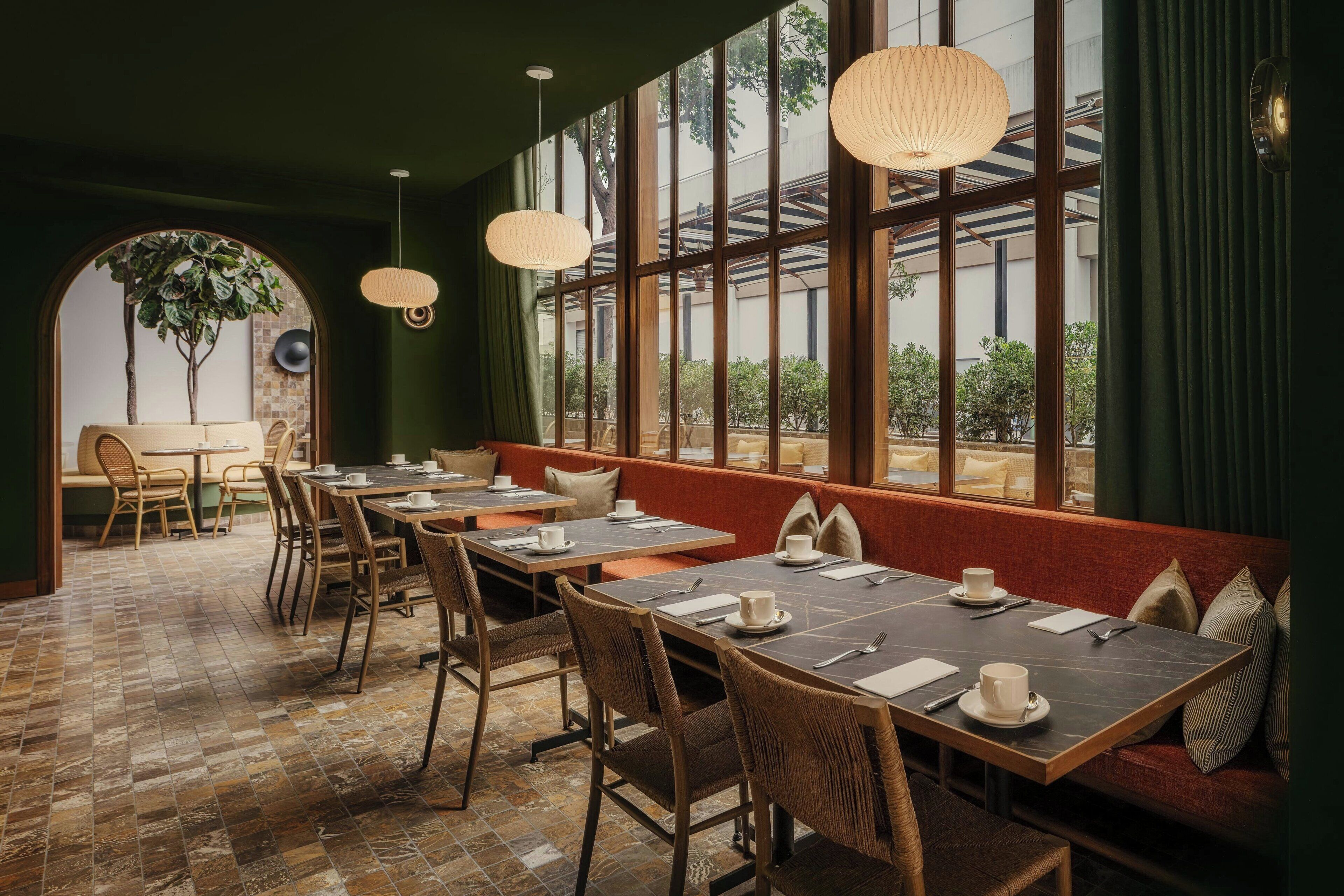 A restaurant with a long dining area, booths, and a large window with a view of greenery.