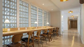 A long, wooden reception desk with chairs, a patterned glass partition, and pendant lighting.