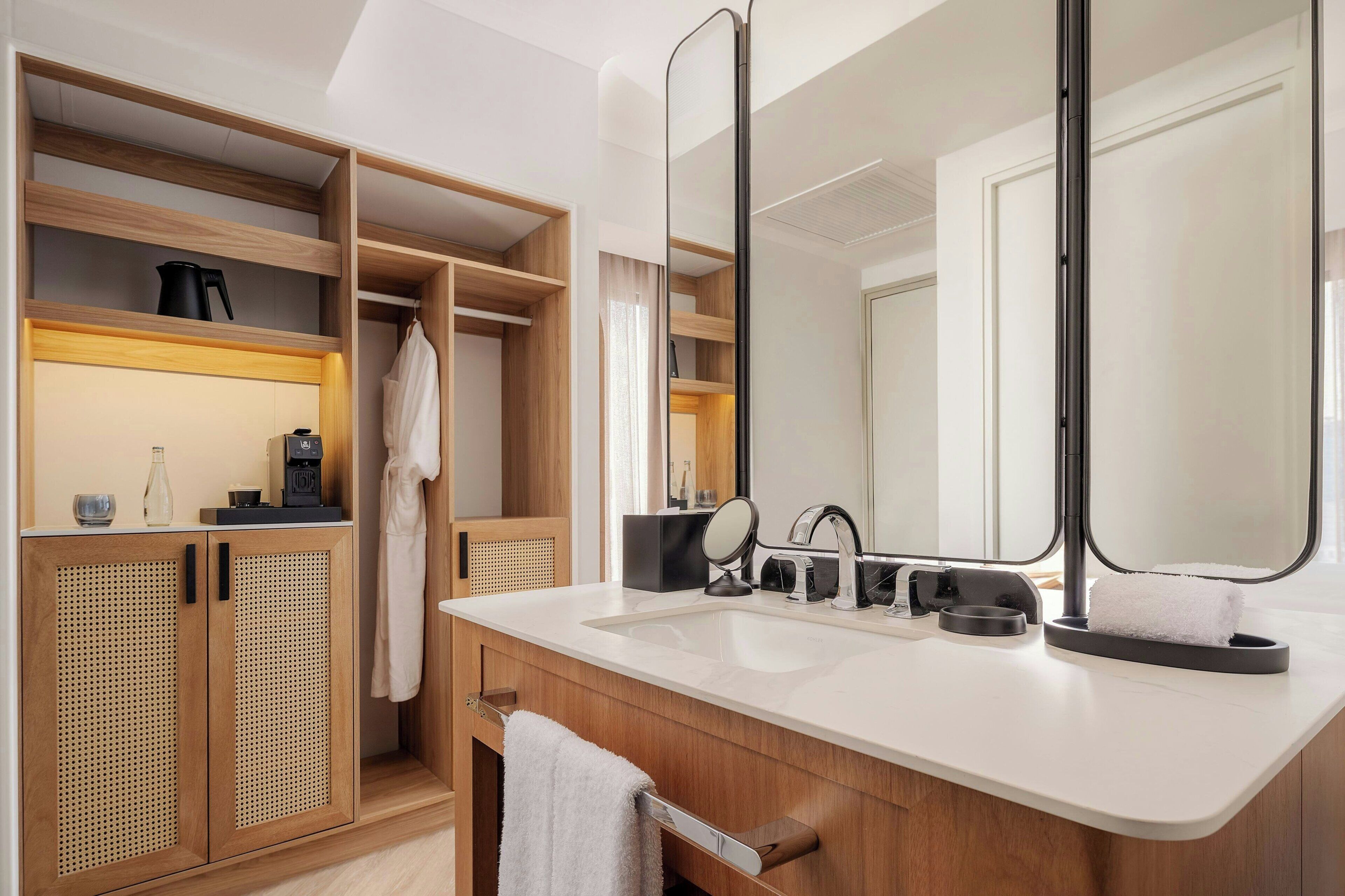 Un baño moderno con tocador de madera, dos lavamanos, un espejo grande y un vestidor.