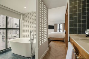 A modern bathroom with a freestanding bathtub, a shower enclosure, and a large window offering a city view.