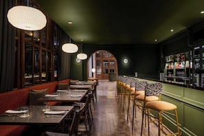 Un restaurant amb seients a caixa, taules altes i una zona de bar.
