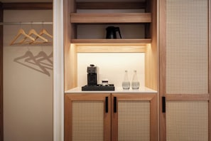A wooden cabinet with a coffee maker and two bottles on top.