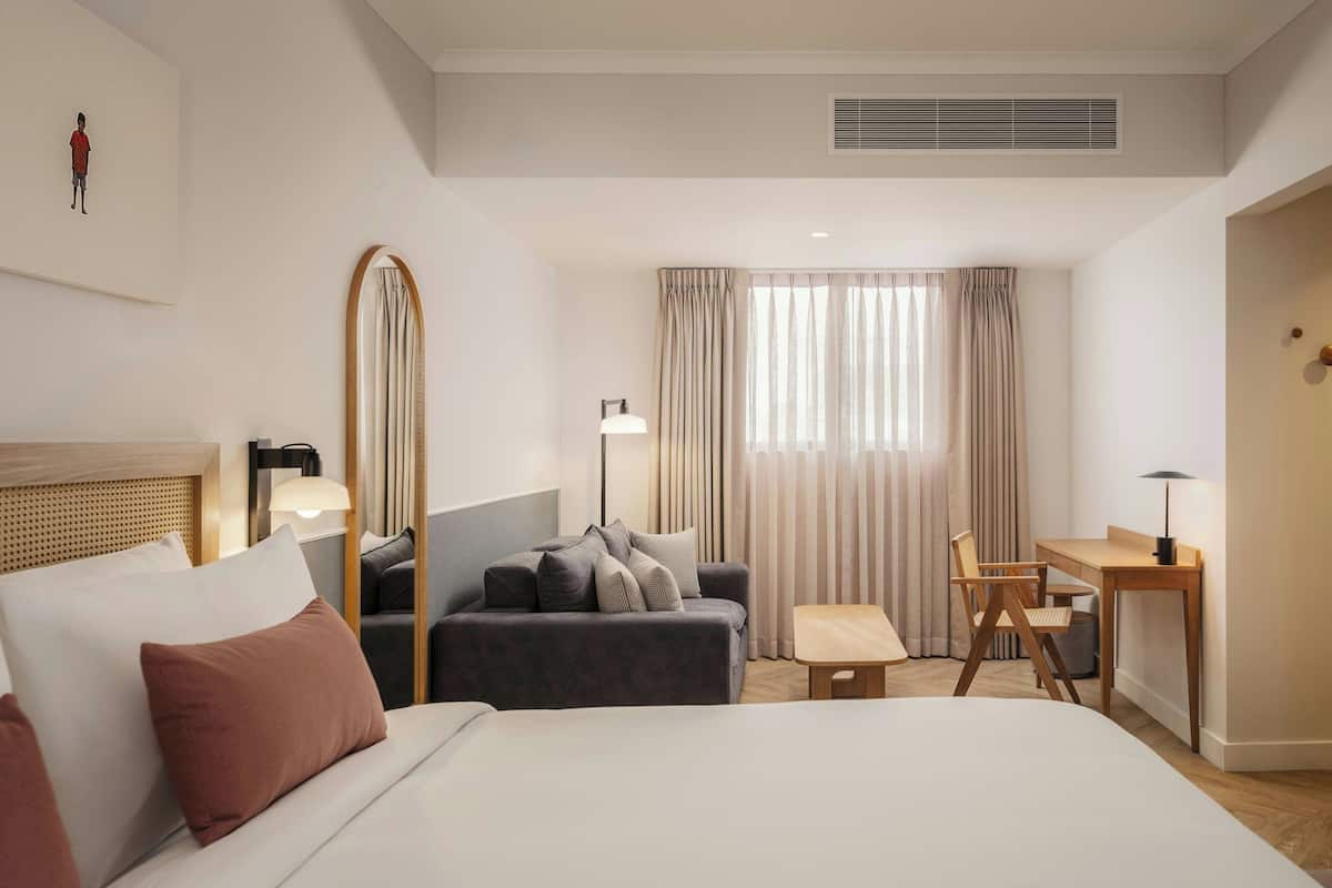 A hotel room with a bed, a sofa, a desk, and a chair.