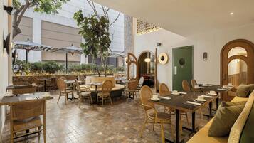Un restaurante con terraza, mesas, sillas y una puerta verde.