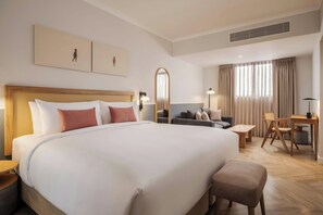 A hotel room with a large bed, a sofa, a desk, and a chair.