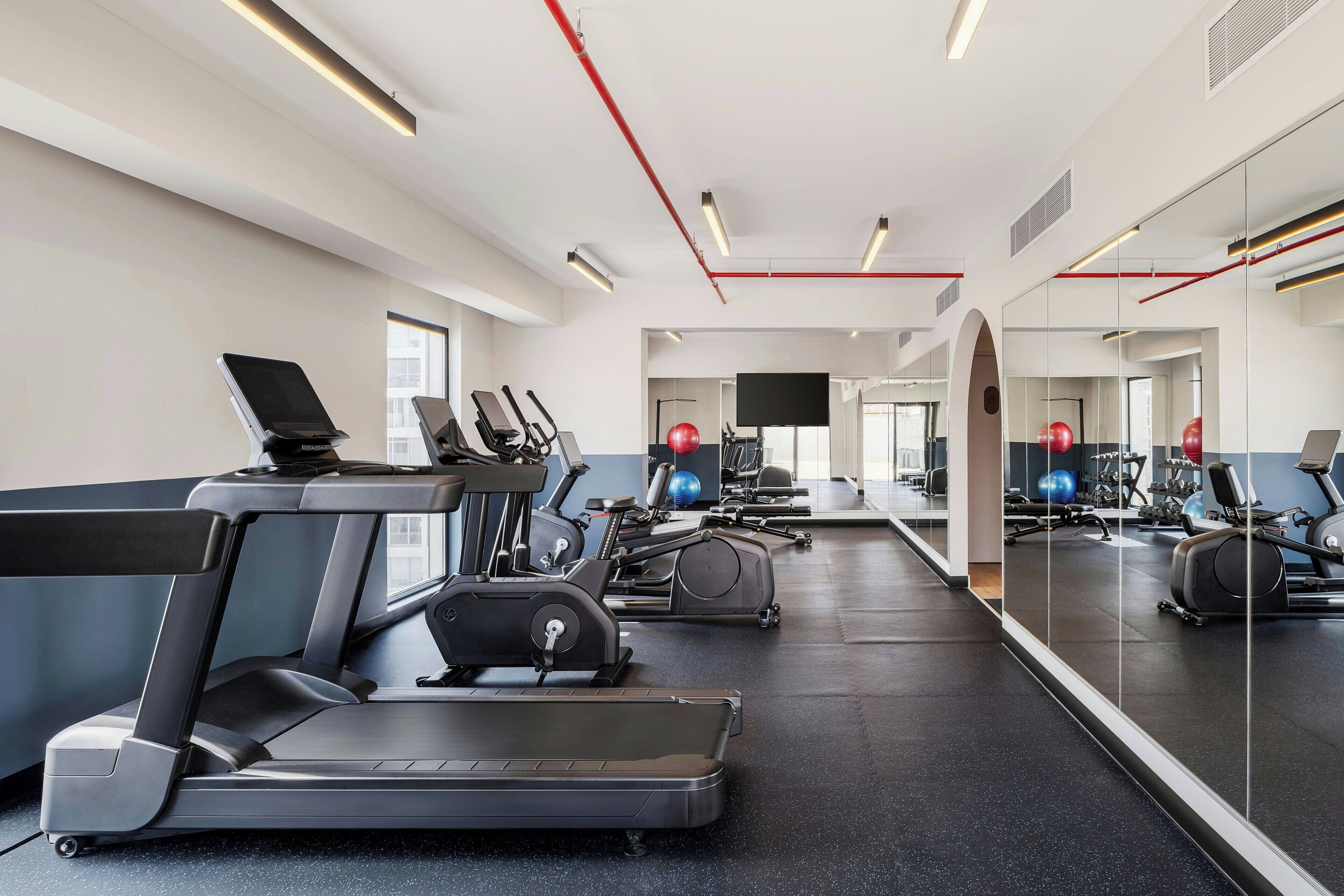 A gym with treadmills, exercise balls, and mirrors.