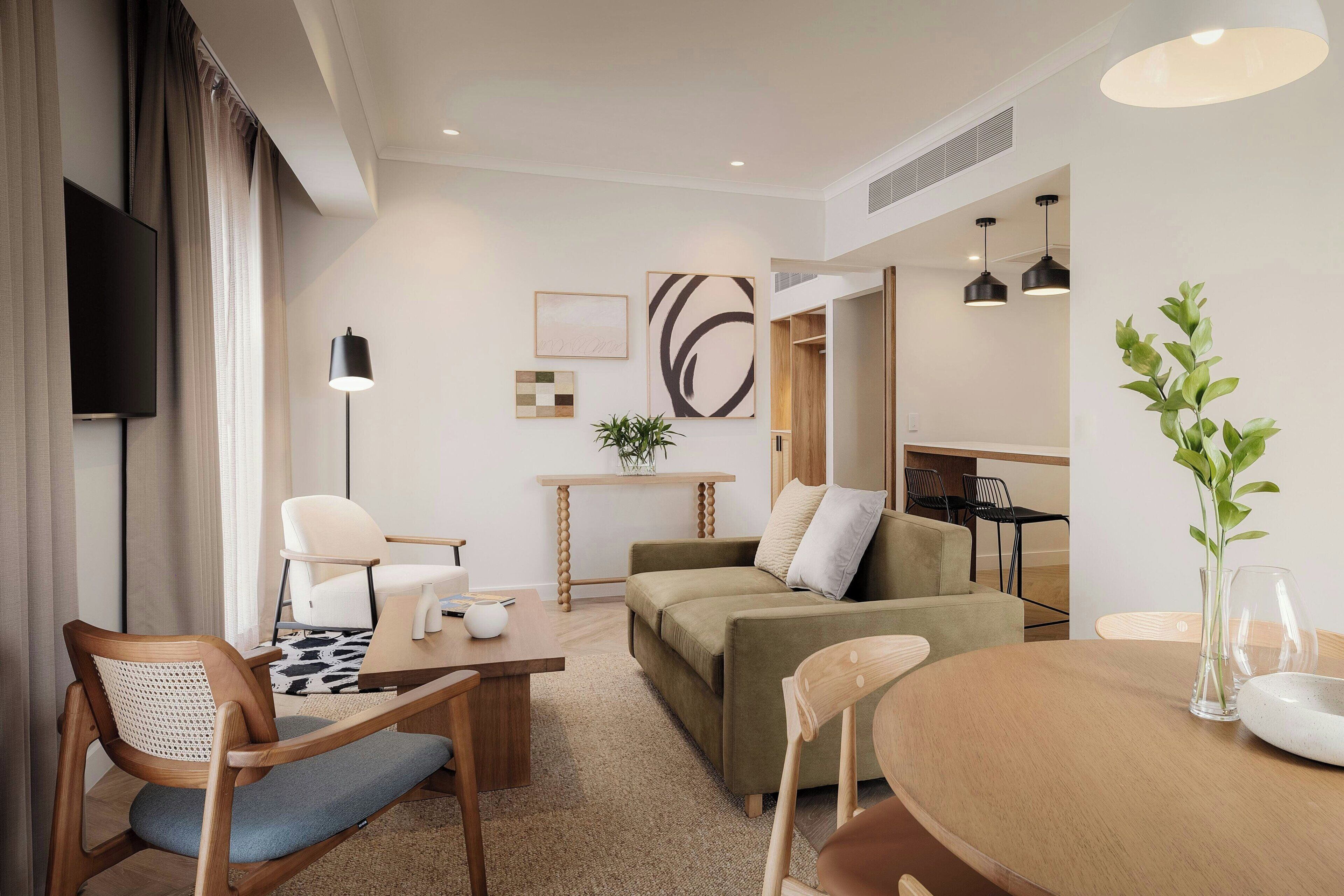 A modern living room with a sofa, chairs, a coffee table, and a TV.