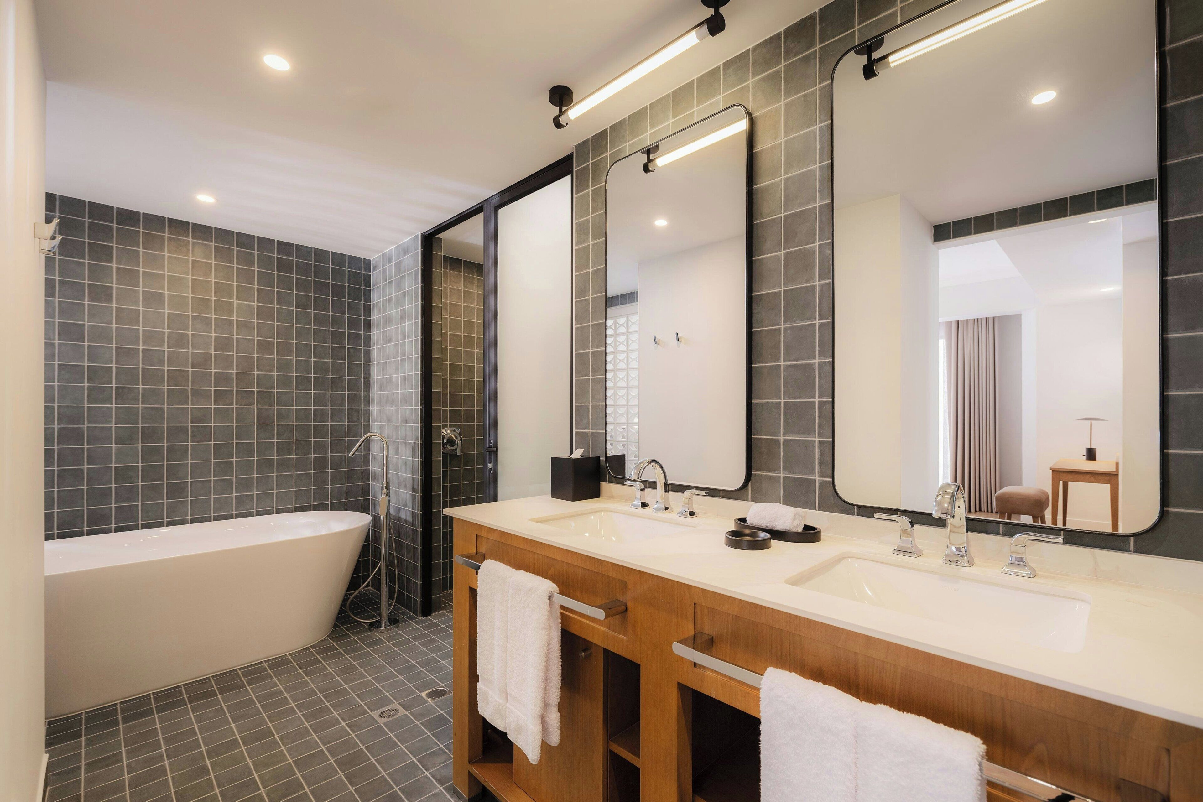 Une salle de bain moderne avec une baignoire sur pieds, deux vasques et un grand miroir.