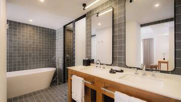 Une salle de bain moderne avec une baignoire sur pieds, deux vasques et un grand miroir.