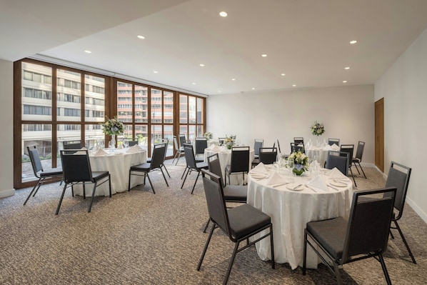 A conference room with round tables, chairs, and large windows with a city view.