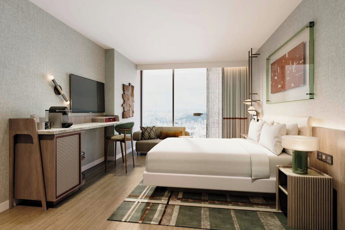 Een moderne hotelkamer met een groot bed, een bureau met een flatscreen televisie, uitzicht op de stad en een groot raam.