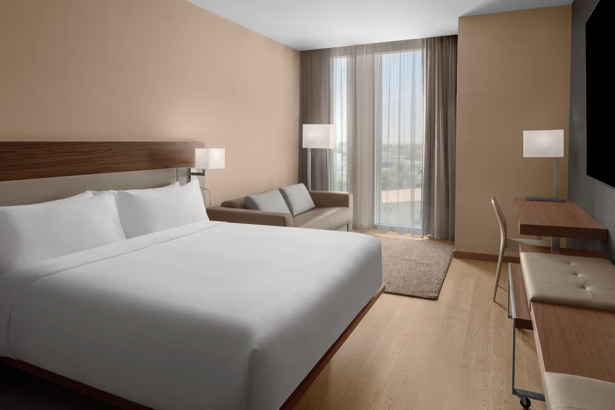 Une chambre d’hôtel avec un grand lit, un canapé, un bureau et une télévision.