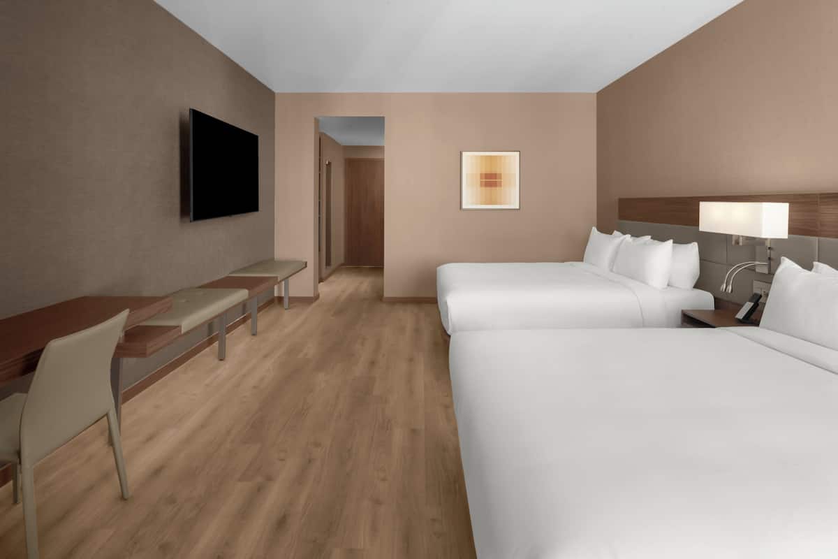 Une chambre d’hôtel équipée d’un lit, d’un bureau, d’une chaise, d’une télévision et d’une table de chevet.